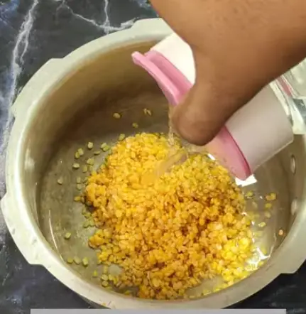 Add ½ cup washed moong dal and water to a pressure cooker.   